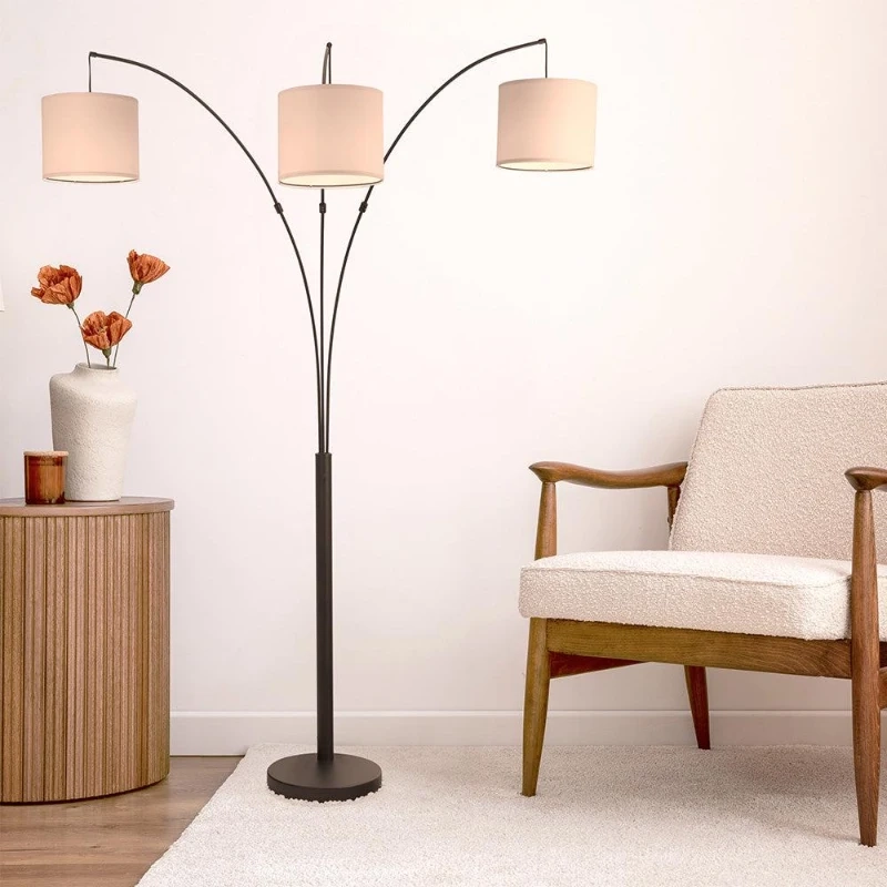 Modern living space with arc floor lamp featuring three fabric drum lampshades.