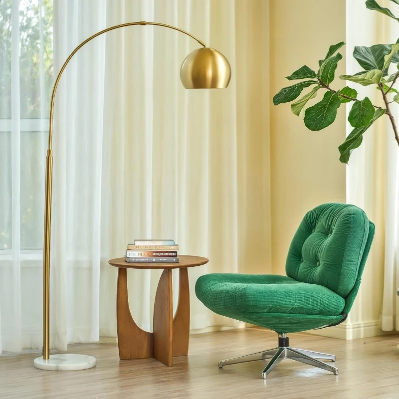 Modern living room with gold arc floor lamp featuring marble base beside green chair and table.
