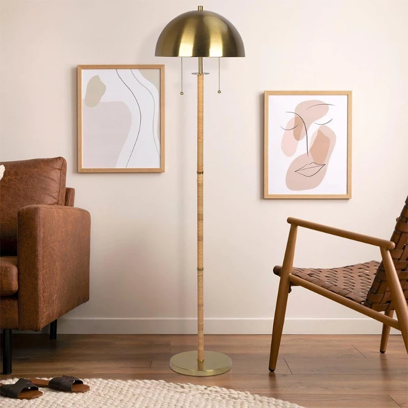 Modern living space with brass floor lamp and dome shade, beside brown sofa and wall art.