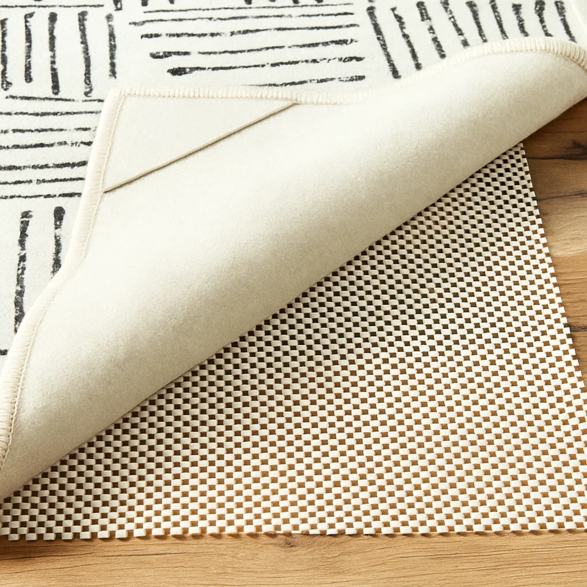 Rubber waffle-patterned rug pad underneath an area rug for anti-slip protection on wooden flooring.