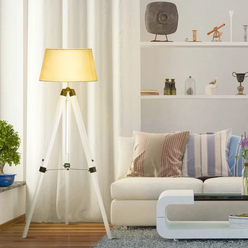 White tripod floor lamp in a bright living room with sofa and shelves.