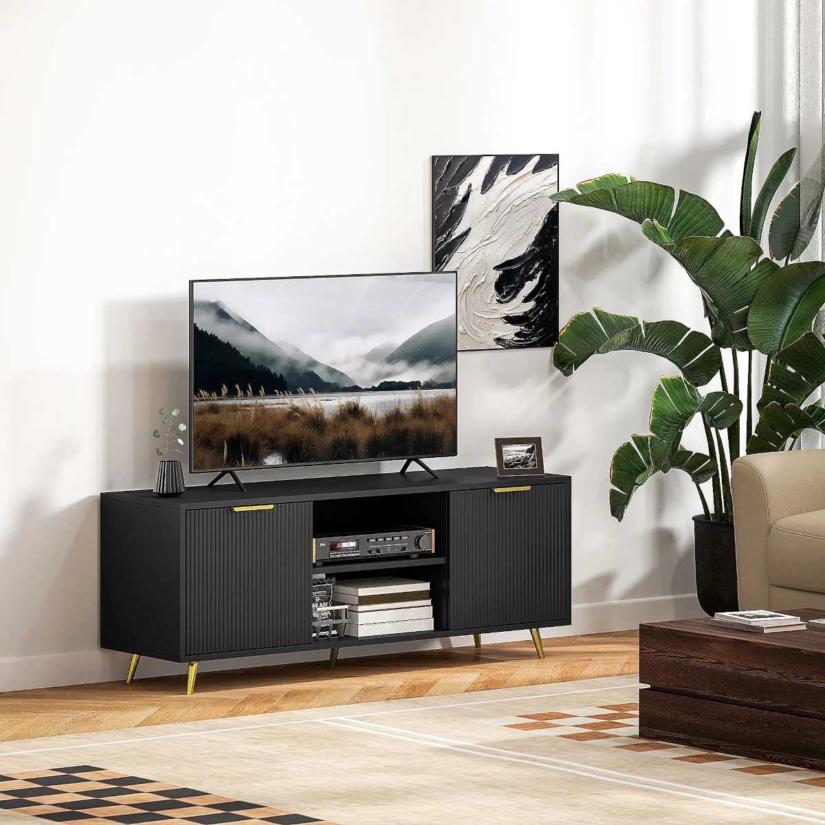 Black TV stand with gold handles, fluted doors, and open shelving storing electronics and books in living room.