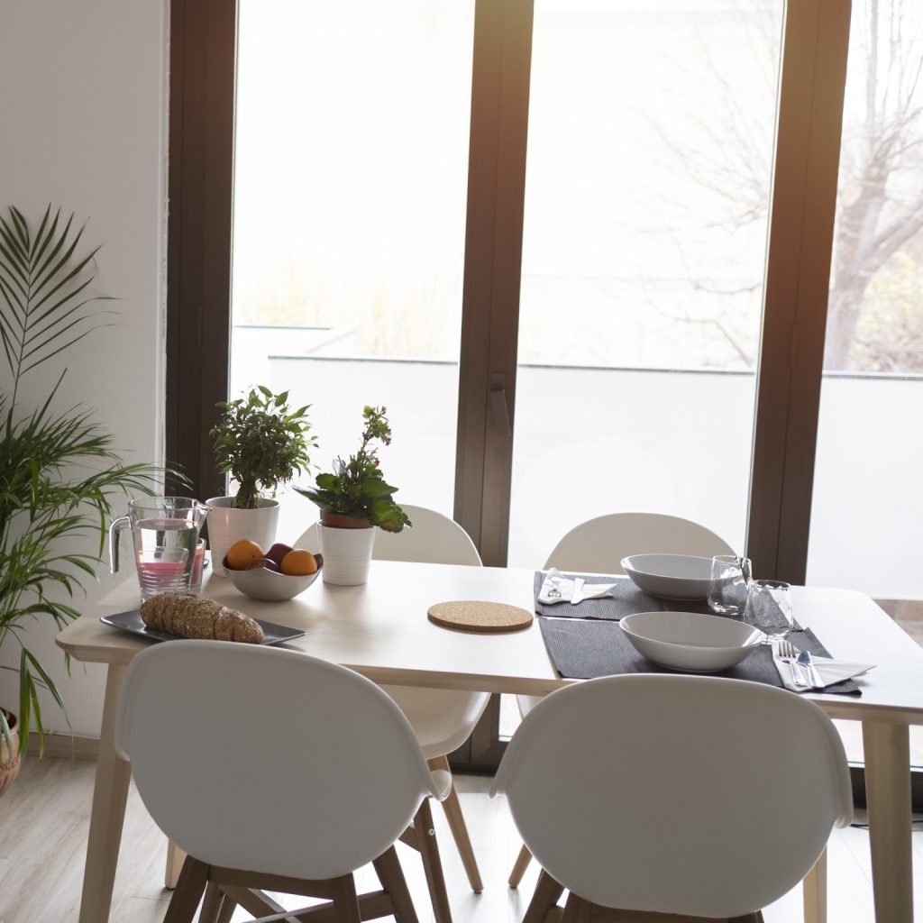 Bright small dining room with round table, wall art, and flowers