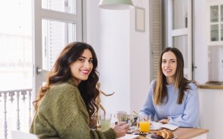 Two women enjoying breakfast at a small kitchen nook with natural light and modern decor.
