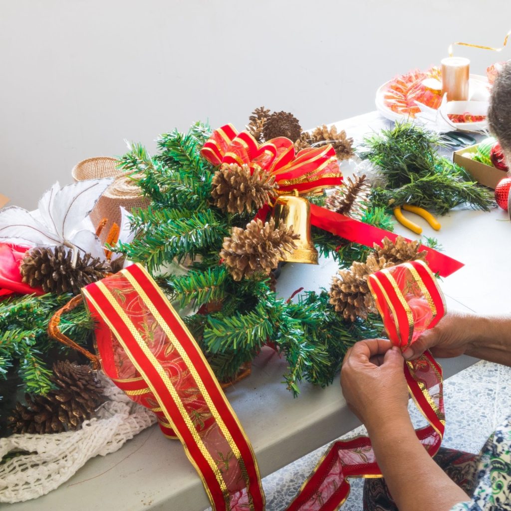 women doing christmas decoration with ribbons and garland