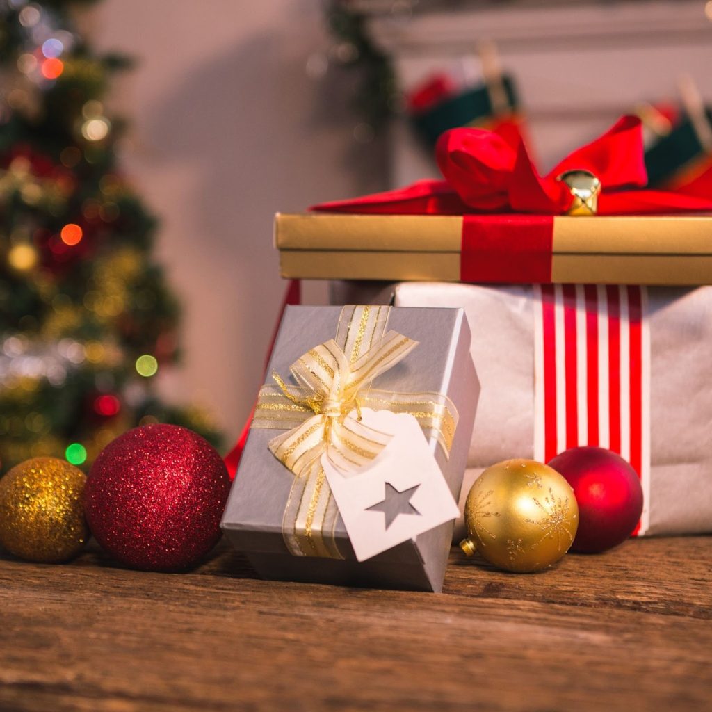 Wrapped Christmas presents with red ribbons and ornaments on festive table