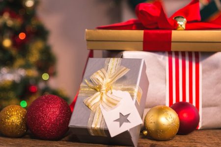 Wrapped Christmas presents with red ribbons and ornaments on festive table